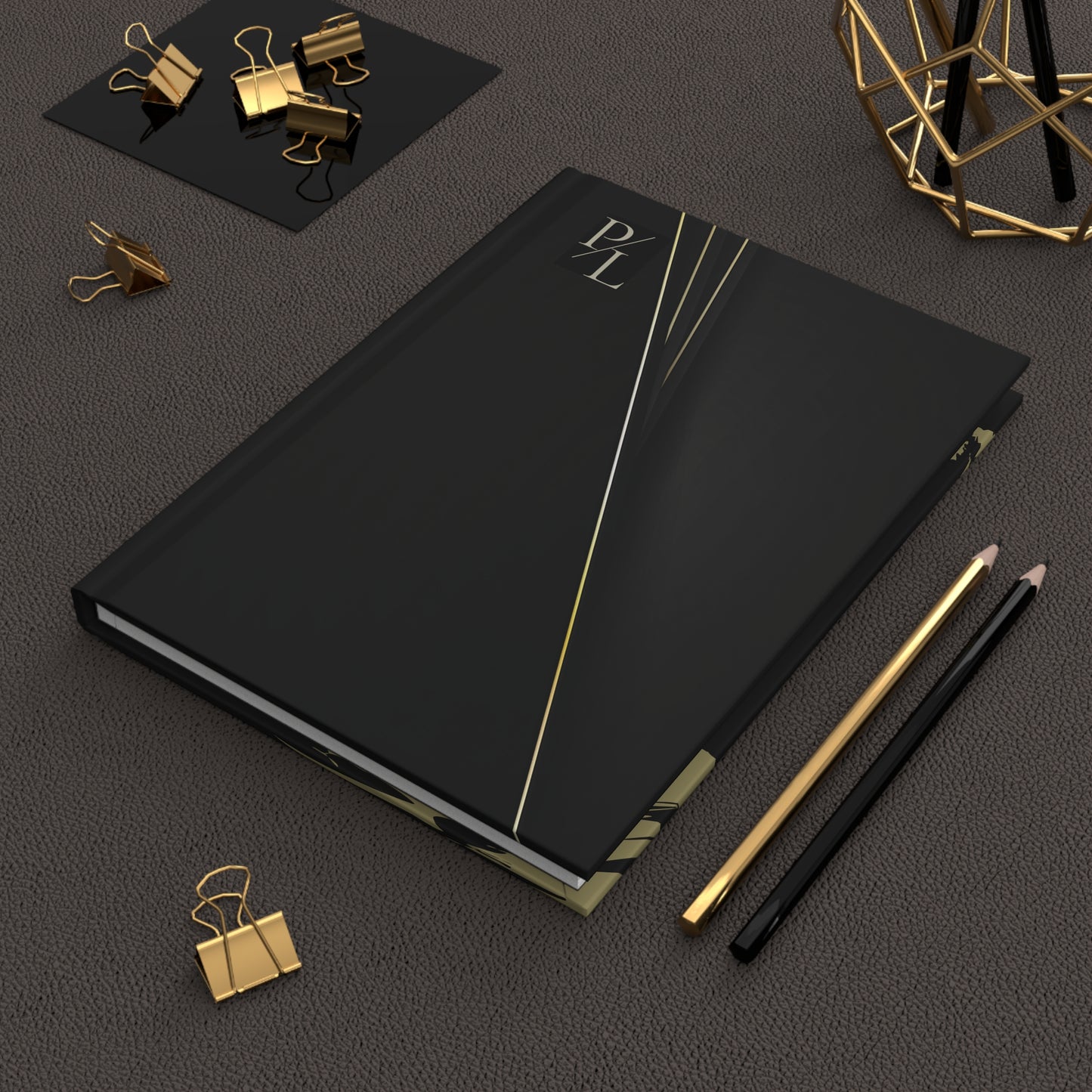 Black notebook with gold accents on a dark surface with office supplies.